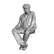 A seated man wearing flatcap