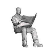 A seated man reading newspaper