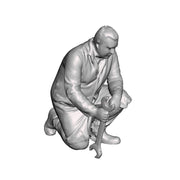 A fitter kneeling with spanner