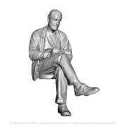 A male figure seated with notebook