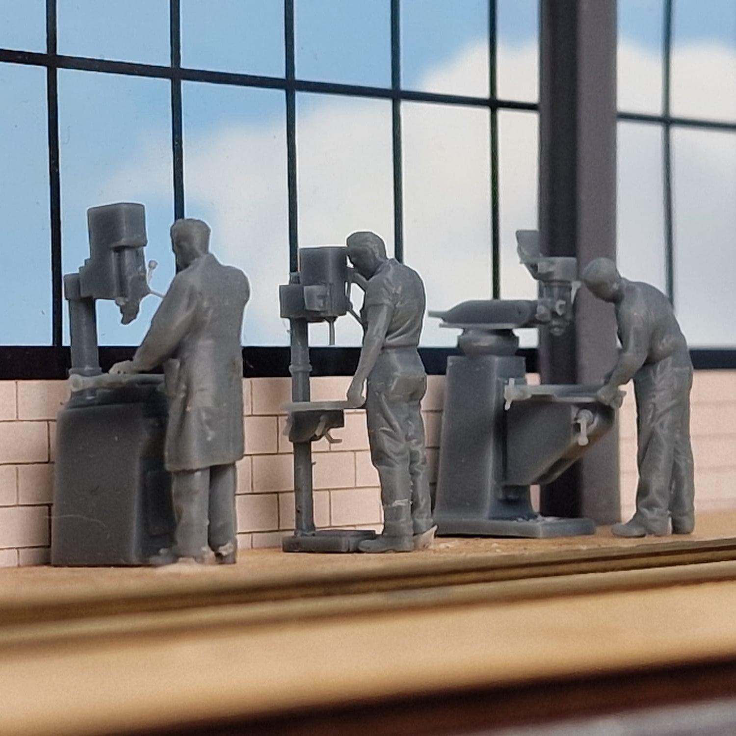 Model of workers operating machinery in a factory setting with large windows.