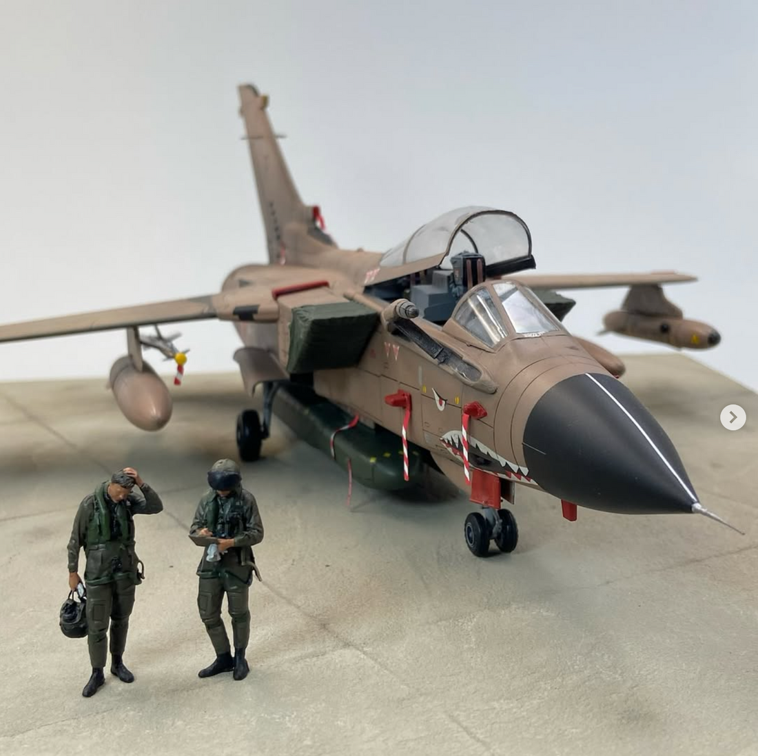 Model of a military jet with two figures in front on a neutral background