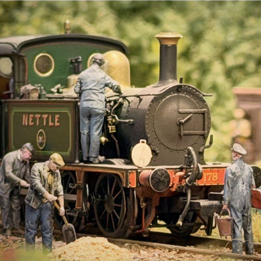 Model steam locomotive with workers around it on a track